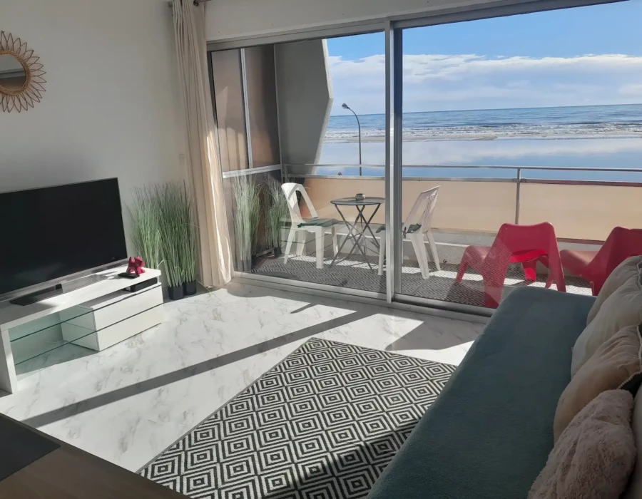 Vue du salon avec smart TV et du balcon vue sur mer de l’Écrin de sérénité