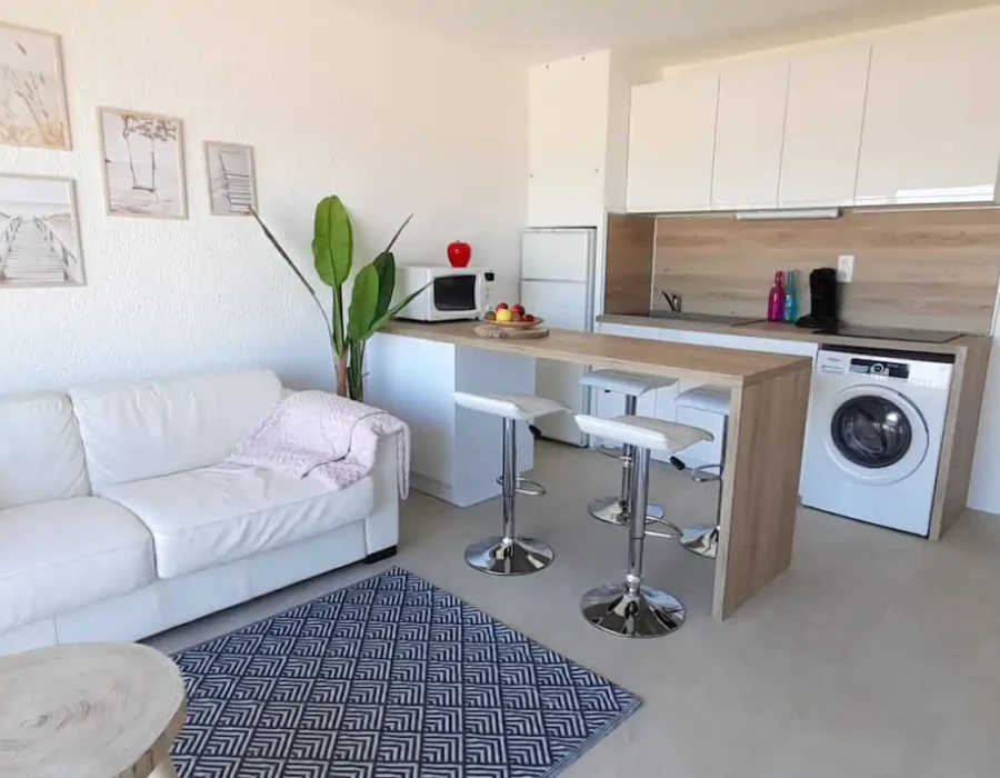 Vue de la cuisine équipée, de la machine à laver et du canapé-lit de l'appartement Face à la Mer