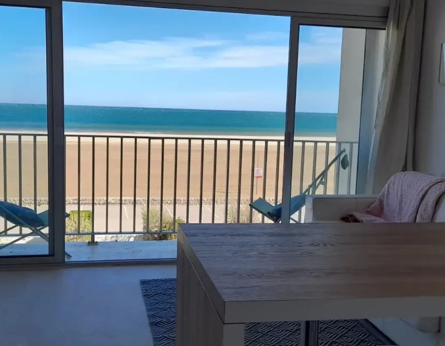 Vue de la cuisine équipée, du balcon et du canapé-lit de l'appartement Face à la Mer